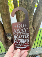Load image into Gallery viewer, Go Away! I'm busy reading Monster Fucking... Door Hanger
